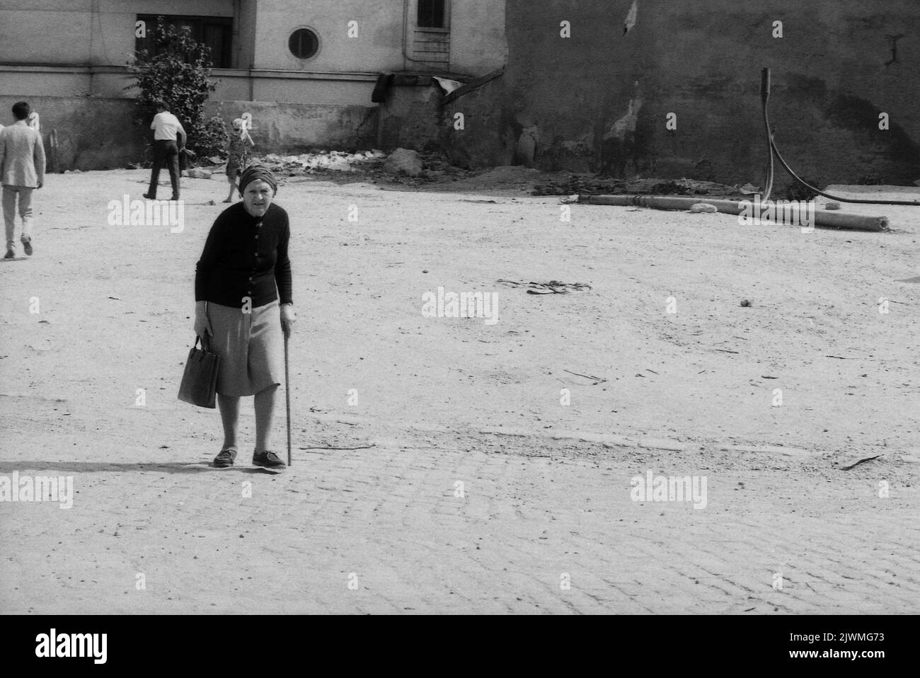 Bucarest, Roumanie, juin 1990. Une femme âgée marche lentement dans une rue du centre de la capitale, quelques mois après la chute du communisme. La zone s'est à peine échappée d'être complètement démolie pour l'un des plus grands projets de systématisation de Ceausescu, le Centre civique. Derrière elle, certains bâtiments historiques sont encore debout. Banque D'Images