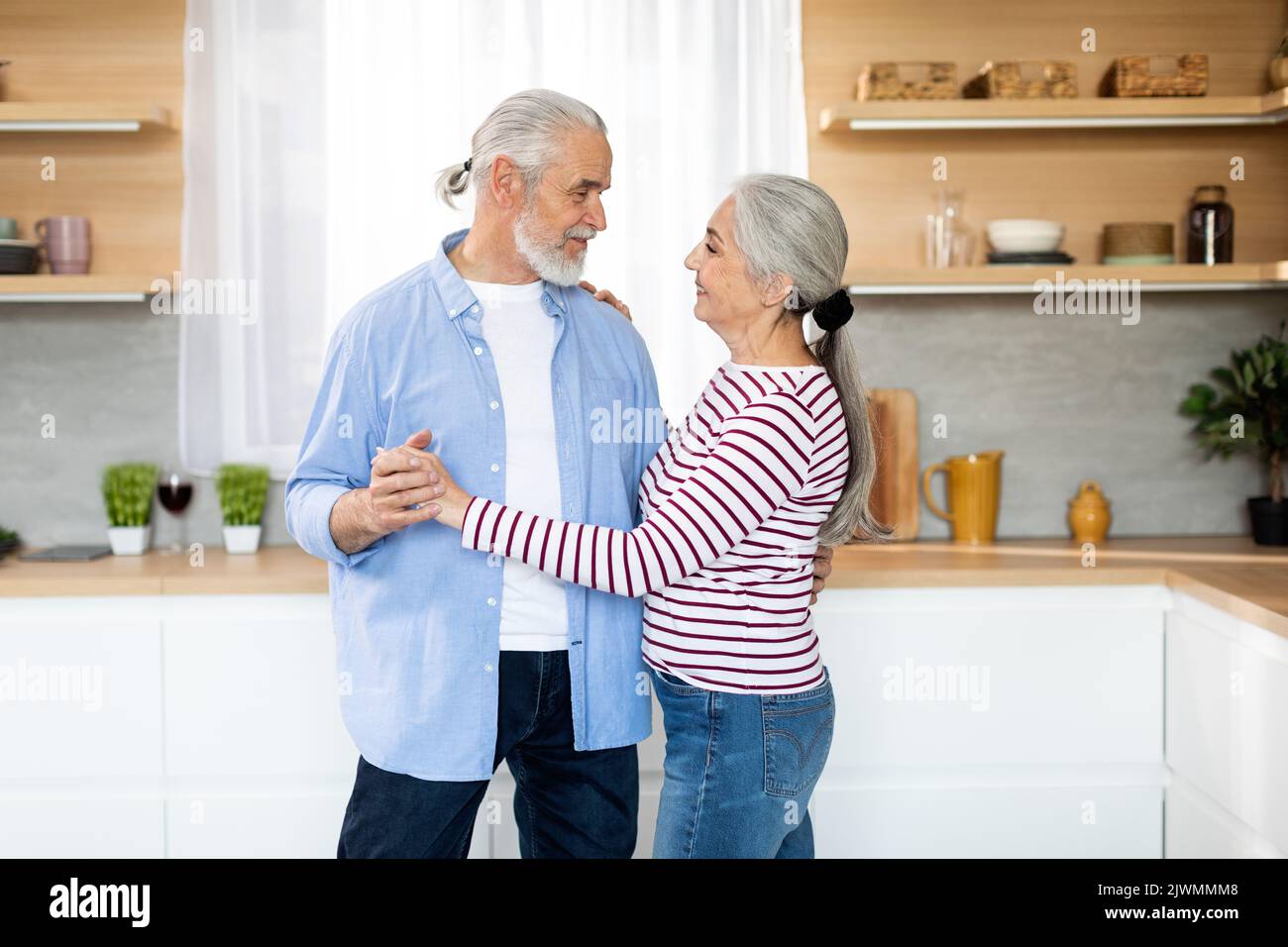 Portrait d'un couple romantique senior dansant ensemble dans la cuisine intérieure Banque D'Images