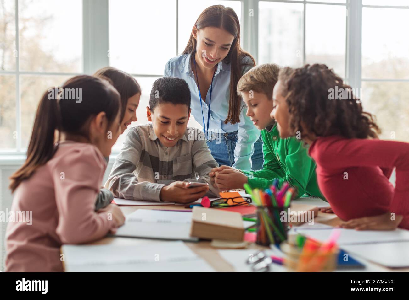 École multiethnique des enfants et des enseignants utilisant un smartphone dans la classe moderne Banque D'Images