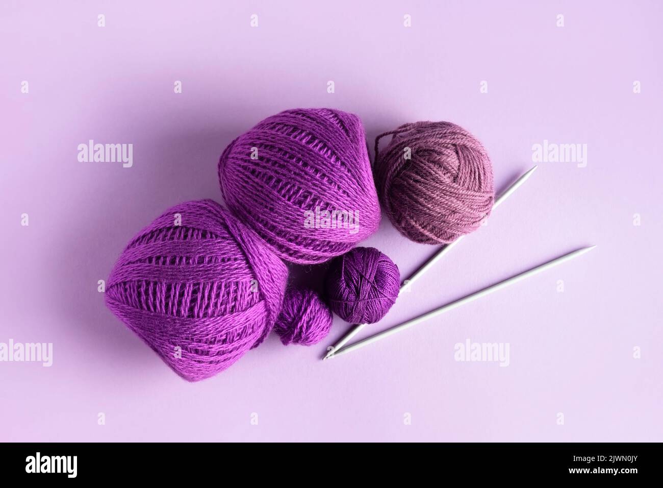 Lilas violet et laine tricotée rose sur fond lilas pour tricoter des vêtements chauds et des hobbies Banque D'Images