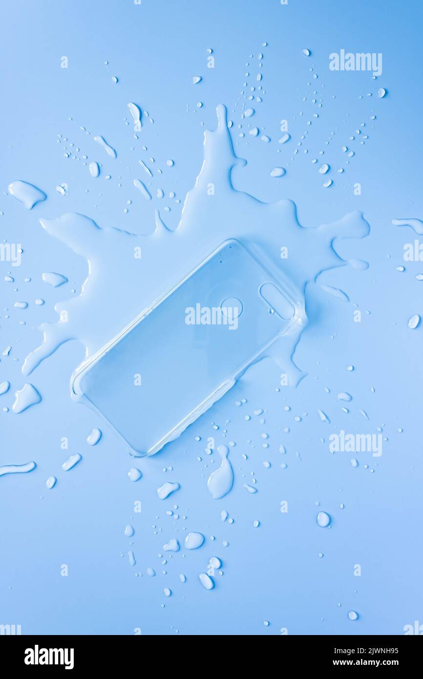 Couvercle arrière transparent pour smartphone dans l'eau renversée sur fond bleu. Copier l'espace. Pose à plat. Vue de dessus. Banque D'Images