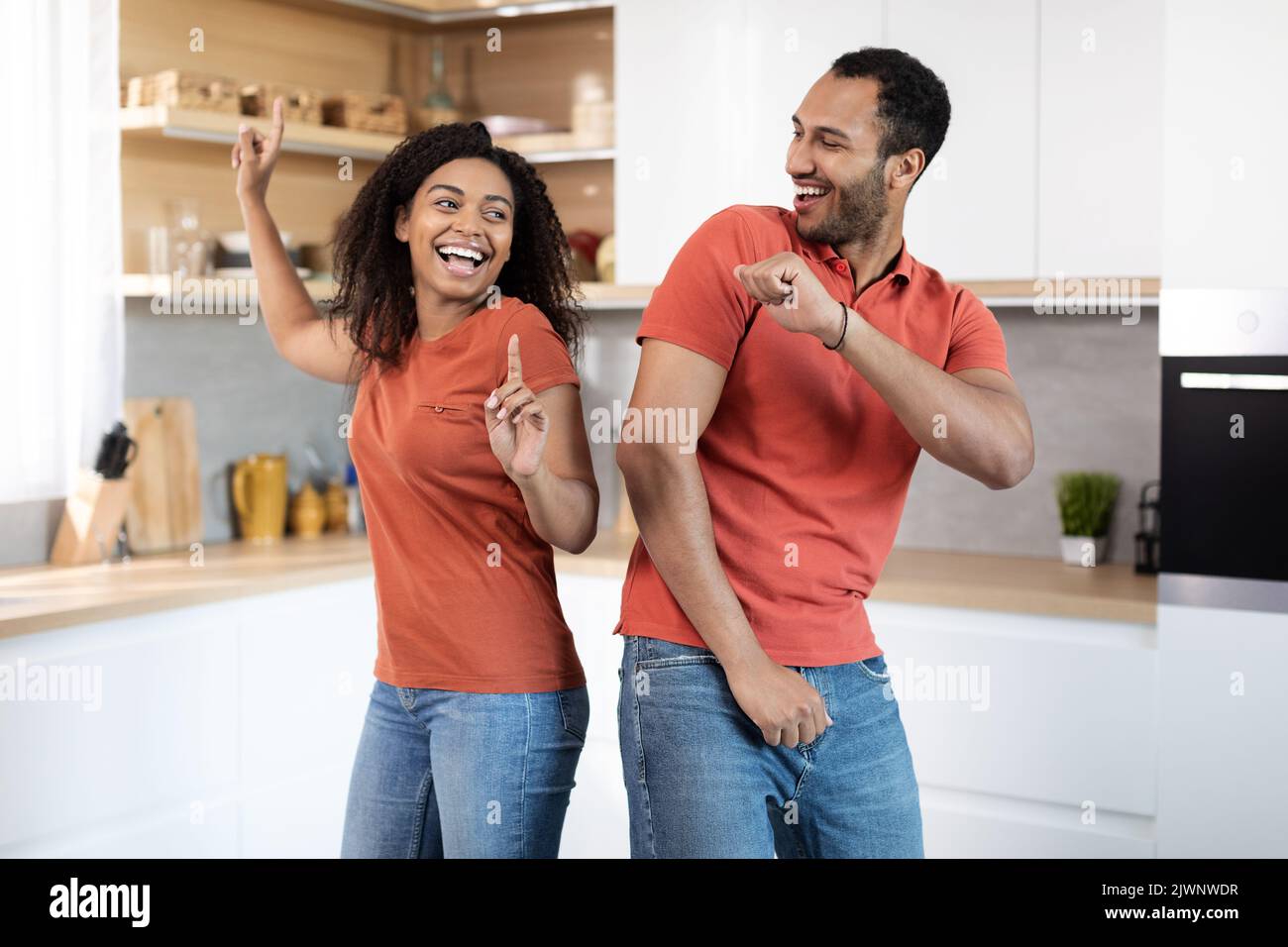 Joyeux jeune afro-américain gars et femme dans les mêmes t-shirts ont le plaisir et la danse ensemble Banque D'Images