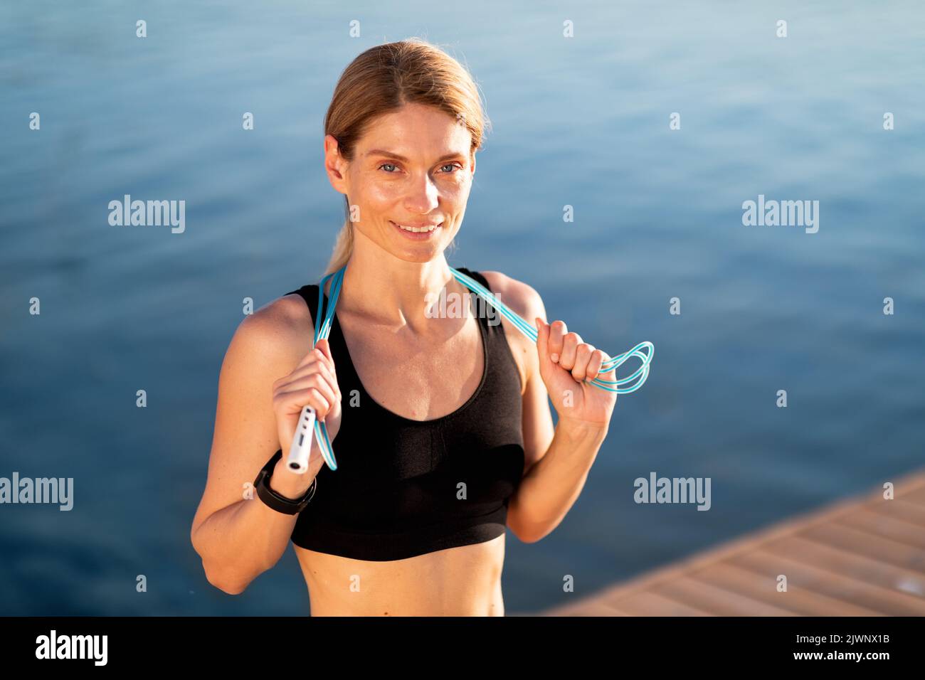 Un style de vie sain. Femme d'âge moyen posant avec corde à sauter pendant l'entraînement en extérieur Banque D'Images