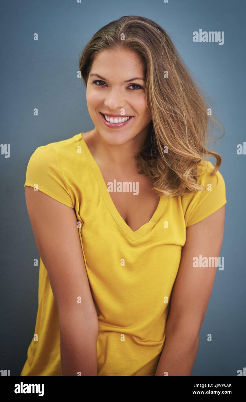 La vie est au sujet d'être heureux. Une jeune femme posant contre un mur gris. Banque D'Images