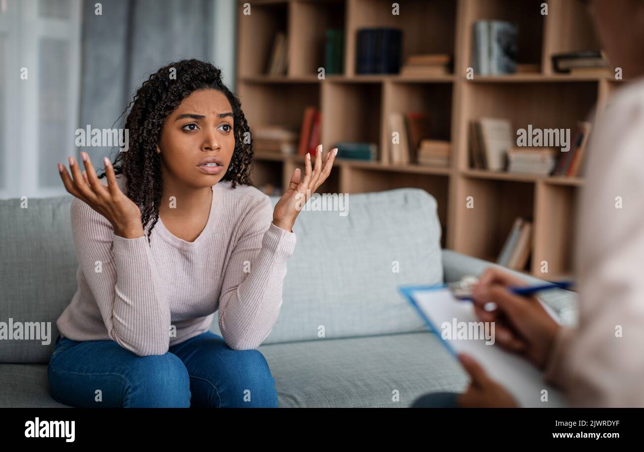 Psychothérapie. Profesée triste émotionnel jeune femme noire regardant la médecin européenne dame dans le bureau Banque D'Images