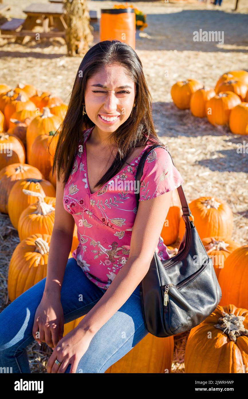 Célébration d'automne Portrait d'une jeune femme asiatique assise sur une grande citrouille dans une ferme Banque D'Images