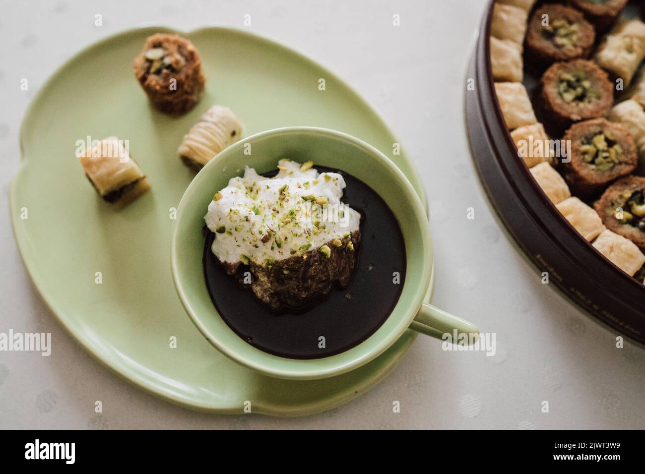 buvez du chocolat dans une assiette et une tasse vertes assorties avec divers desserts à la baklava sur une nappe blanche à pois Banque D'Images
