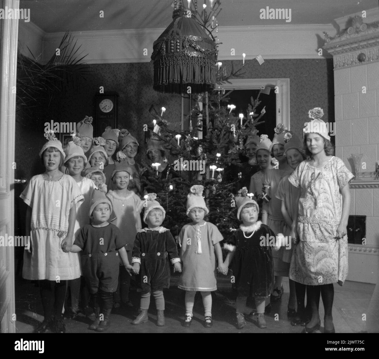 Les cousins et amis du Brundin se sont rassemblés pour piller les arbres de Noël. Tout le monde avait de petits chapeaux en crêpe. La photo prise dans le hall sur Södra Centralgatan 26. Familjen Brundins kusiner och vänner samlade jusqu'au julgranssindring. Alla hade små hattar gjorda av kräpppper. Fotot taget i salen på Södra Centralgatan 26. Banque D'Images