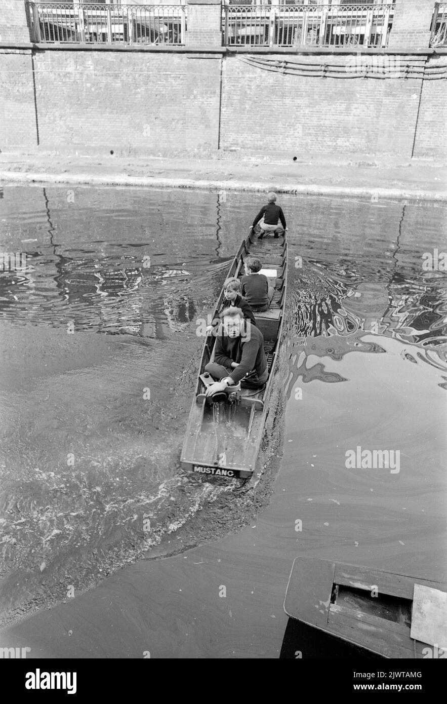 Londres, Angleterre, vers 1967. Un volontaire adulte et trois garçons sont à bord d’un petit bateau appelé ‘Mustang’ qui a un moteur hors-bord. Ils sont tous membres du Pirate Club. Le Pirate Club, un club de canotage pour enfants, a été créé en 1966 à Gilbey’s Wharf, sur le canal Regents, près de Camden, à Londres. Leur pavillon était une ancienne barge et un certain nombre de petits bateaux et de canoës avaient été donnés pour les enfants. Banque D'Images