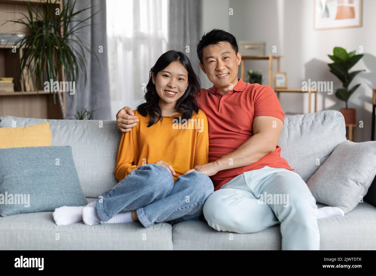 Un couple chinois affectueux se liant sur un canapé à la maison Banque D'Images