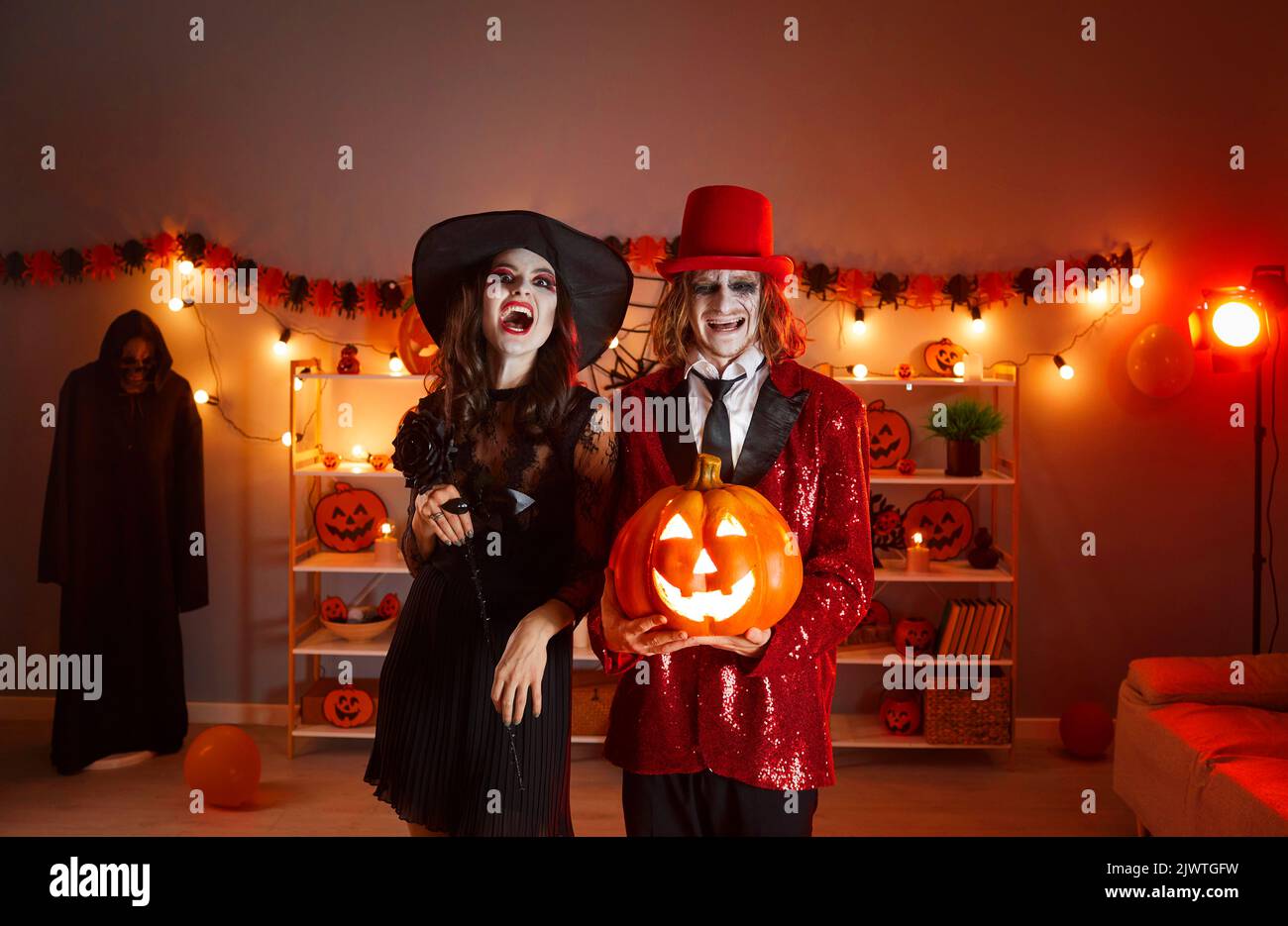 Un jeune couple heureux vêtu de costumes effrayants d'Halloween avec sa Jack-o-lanterne Banque D'Images
