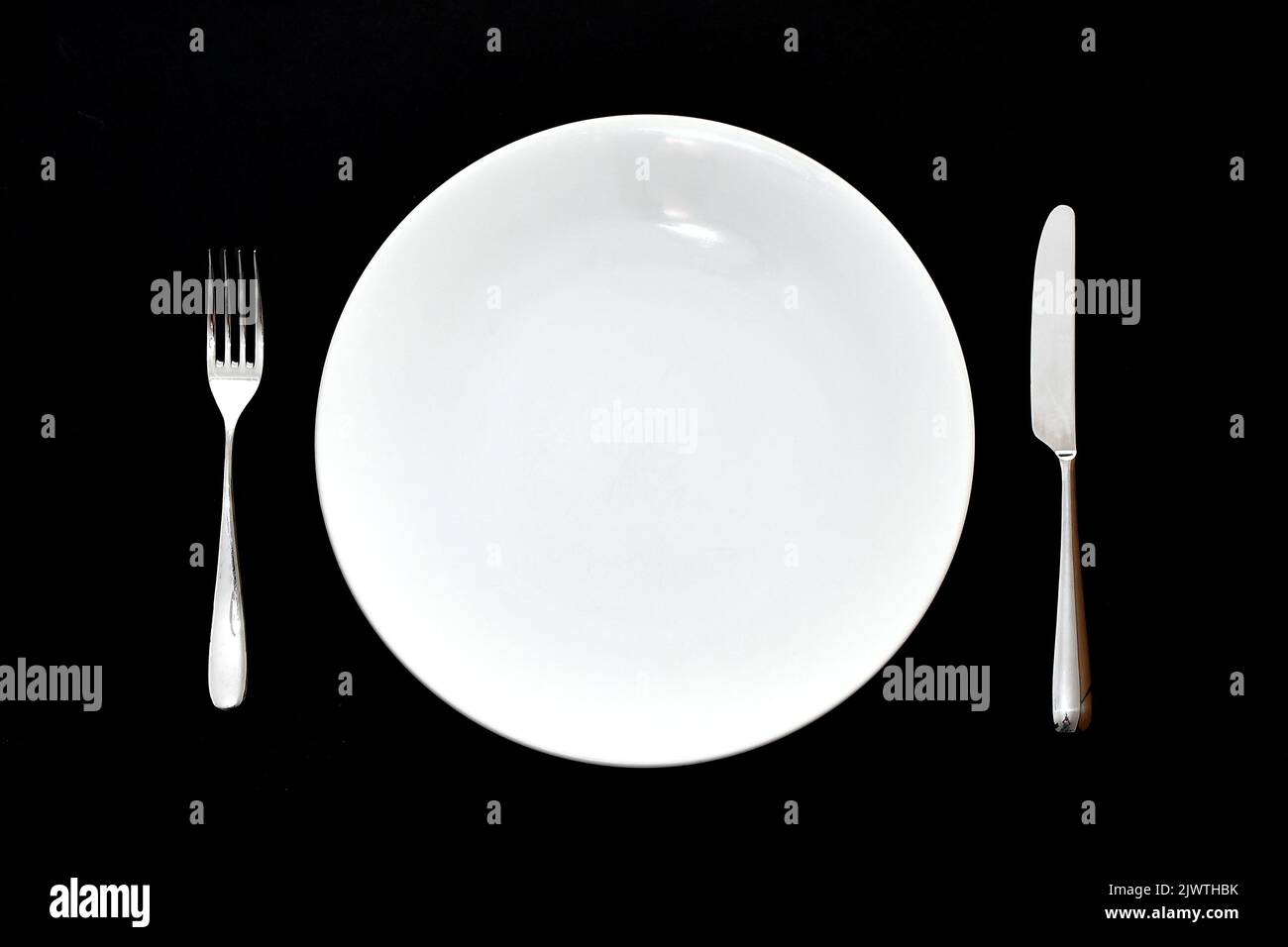 Couteau et fourchette en acier inoxydable et assiette à dîner blanche vide sur un fond de fond Uni. Personne. Banque D'Images