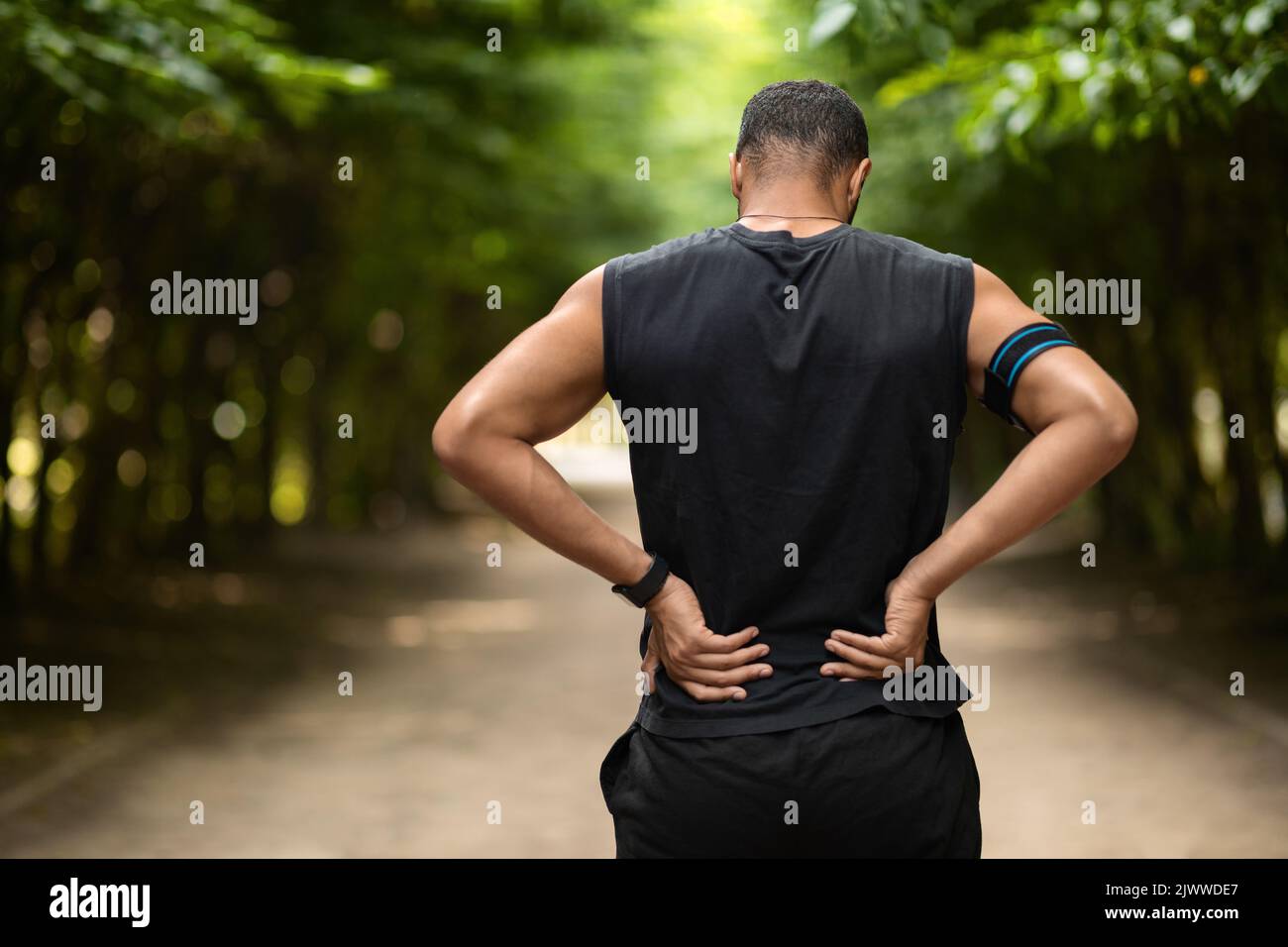 Vue arrière d'un sportif touchant la zone douloureuse sur son dos Banque D'Images