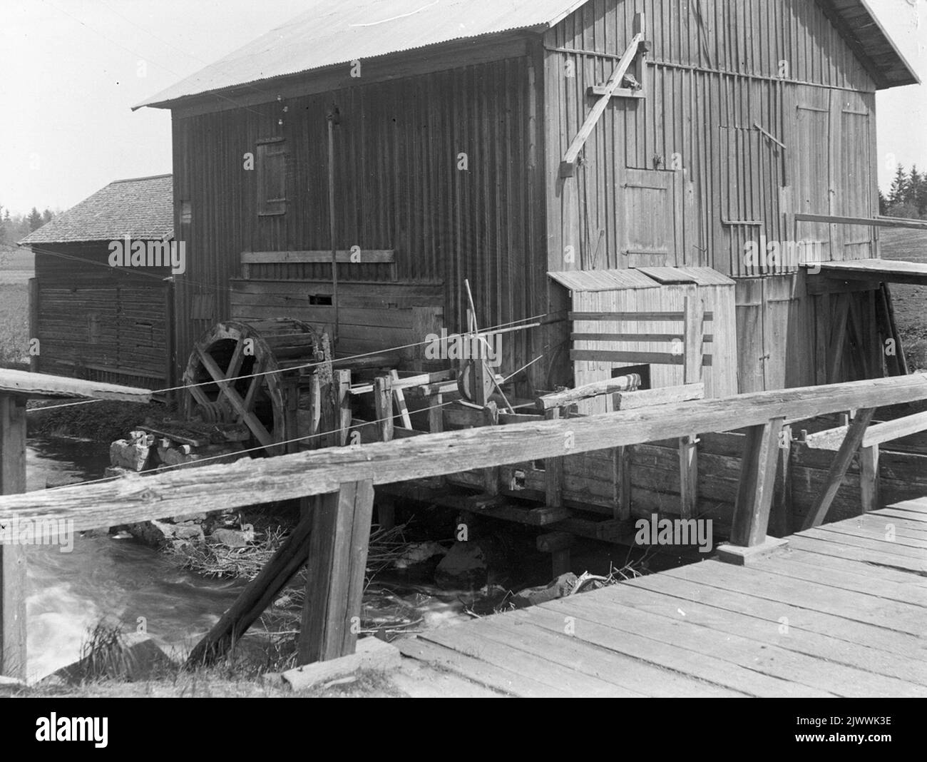 La plantule de Torsåker, anciennement le logo de battage d'Åsmundshyttönna. La grande roue à eau a poussé l'usine de battage et la tige verticale de l'orifice sous le toit vers la roue à eau a été reliée avec un levier à l'usine de battage pour réguler l'alimentation en eau de la roue. La photo est incluse dans Torsåkers photo-société historique. Image page 1. Torsåkers Frörenseri, tidigat, kältik. Det stora vattenhjulet drev tröskverket och den vertikala stången från hålet under taket ner till vattenhjulet var förbunden med en hävstång till tröskverket för reglera vat Banque D'Images