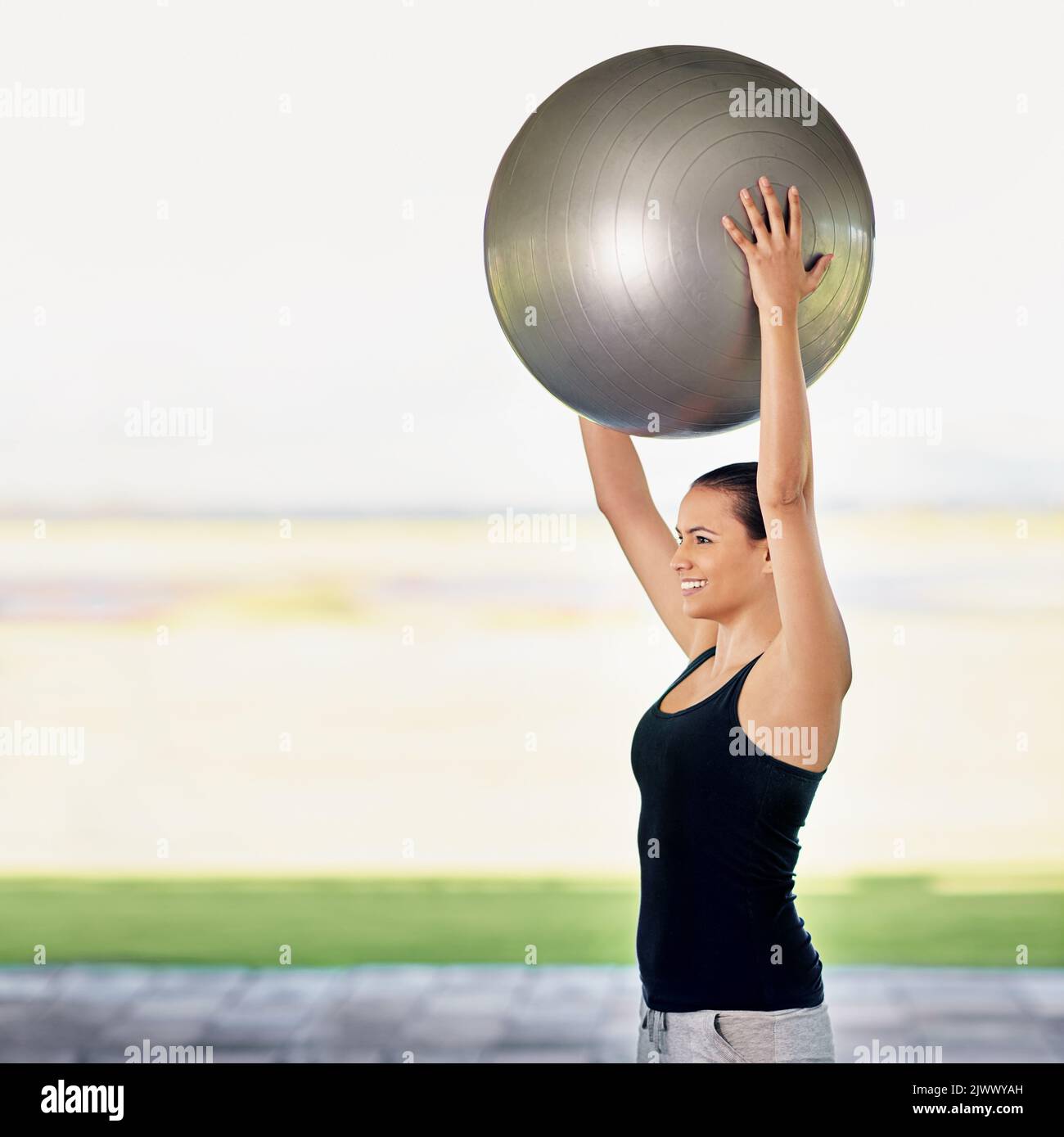 Relever les enjeux. Une jeune femme s'entraîner avec une balle d'exercice. Banque D'Images