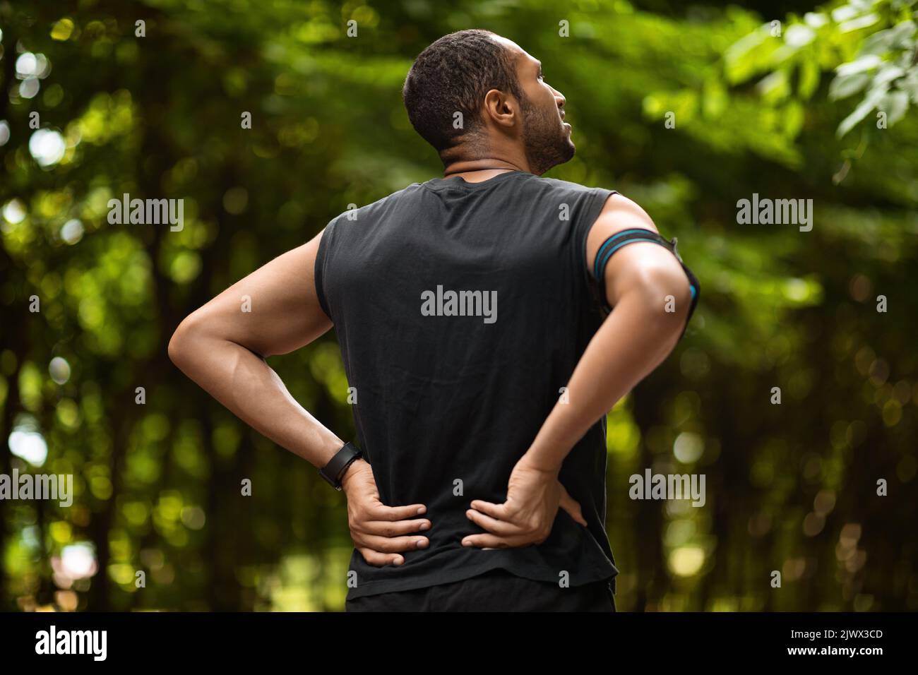 Vue arrière d'un sportif noir touchant la zone douloureuse à l'arrière Banque D'Images
