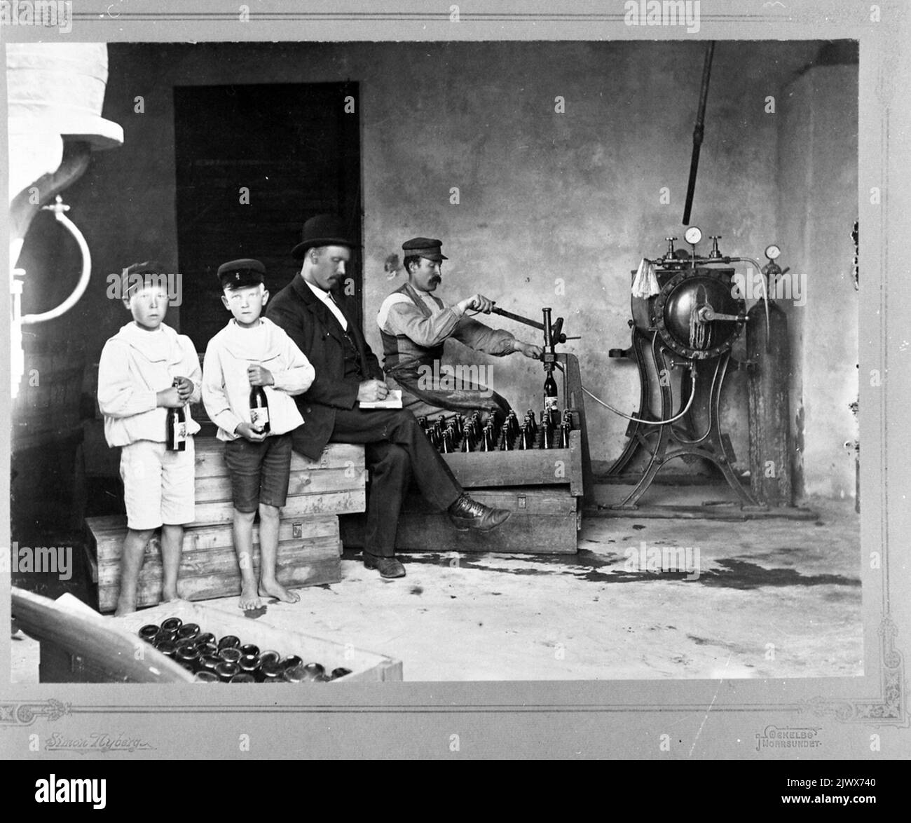 Intérieur de la brasserie Wilanders et de l'usine de boissons gazeuses à Ådala, Kvistholmen. La boisson est déposée sur une bouteille. Le garçon sur la droite est le fils de Jöns Wilander, Karl Gustaf (1896-1987). Interiör från Wilanders Bryggeri och Läskedrycksfabrik på Ådala, Kvistholmen. Djälvälvän. Gossen jusqu'à höger är Jöns Wilanders fils Karl Gustaf (1896-1987). Banque D'Images