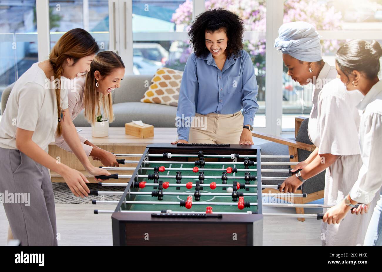 Baby-foot ou football en tant que femmes de bureau jouent un jeu de baby-foot amusant ensemble lors de leur pause déjeuner au travail. Divertissement, amis heureux et féminins dans un Banque D'Images