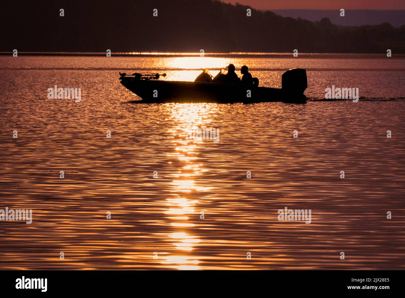 Pêcheurs à l'achigan dans un bateau à l'achigan sur le lac, lever du soleil tôt le matin. Banque D'Images