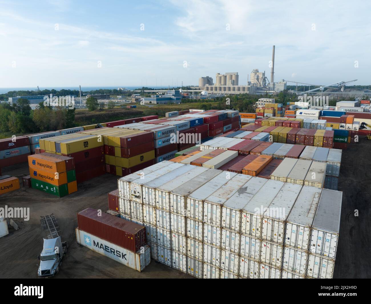 Une vue aérienne au-dessus d'un terminal de conteneurs d'expédition, avec des transporteurs comme les conteneurs Hapag-Lloyd et Maersk dans le chantier de fret dans un secteur industriel. Banque D'Images