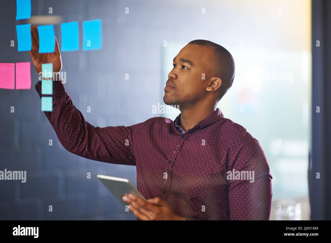 Il est beaucoup plus efficace de créer une disposition d'idées. Un homme concepteur travaillant sur un mur de verre dans le bureau. Banque D'Images