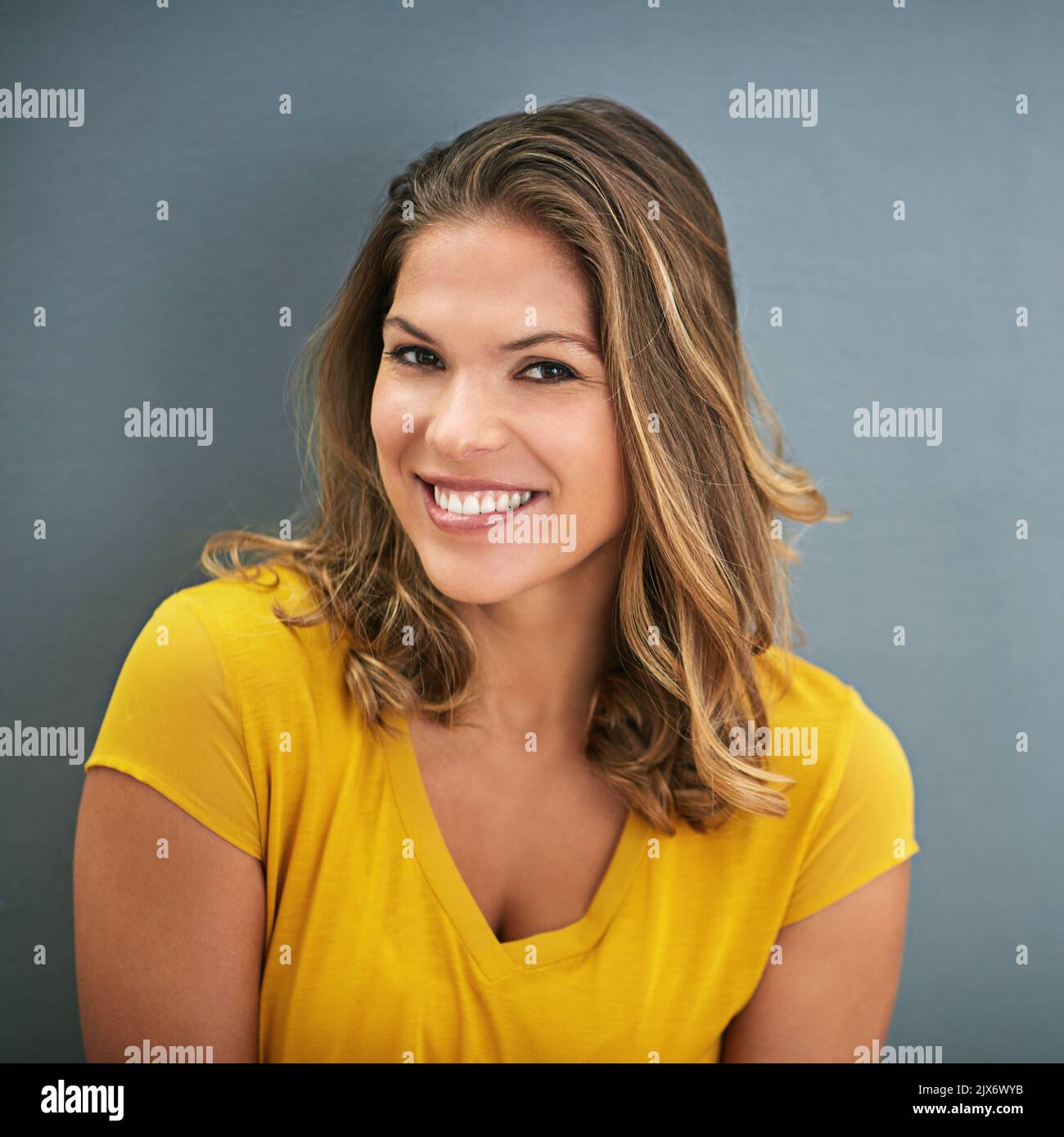 Son regard dit tout. Une jeune femme posant contre un mur gris. Banque D'Images