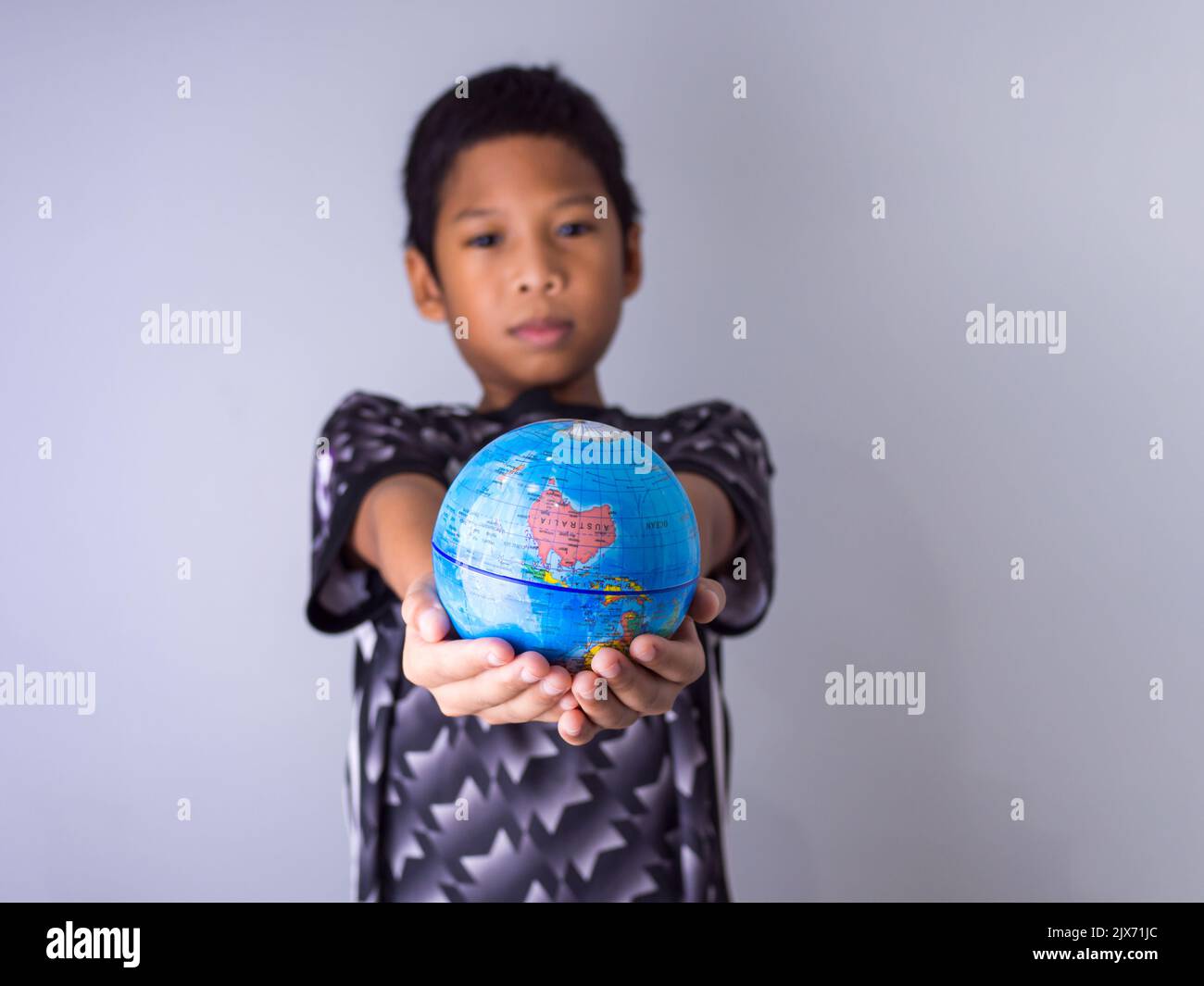 Garçon tenant un globe se démarquer devant montrer la puissance de la nouvelle génération pour continuer à développer notre monde. Banque D'Images