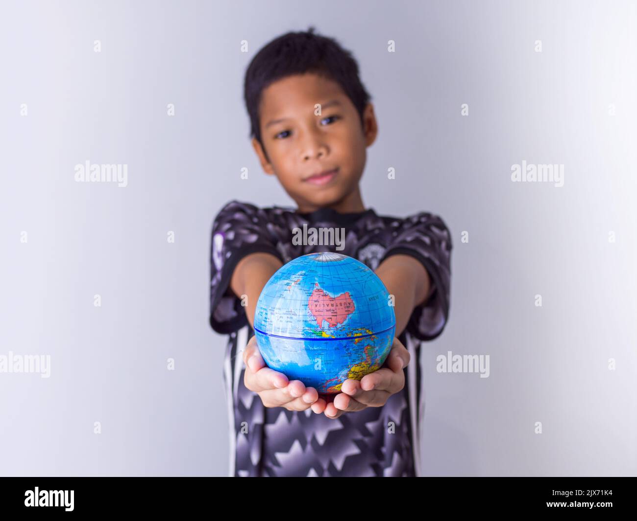 Garçon tenant un globe se démarquer devant montrer la puissance de la nouvelle génération pour continuer à développer notre monde. Banque D'Images