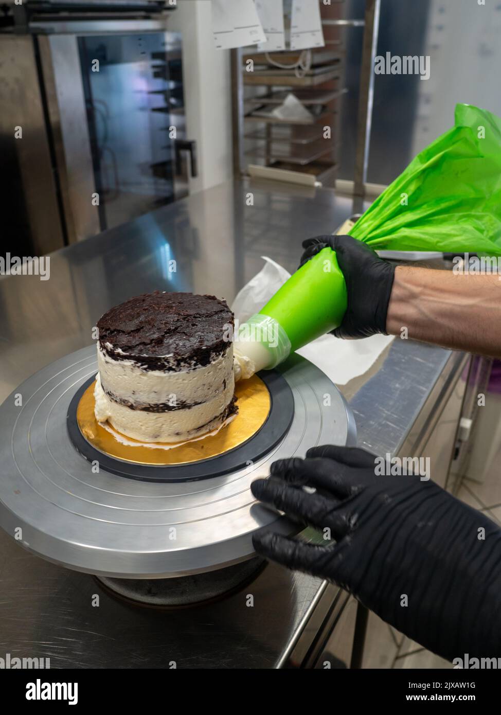 décorateur appliquant de la crème au beurre sur un gâteau dépoli avec un sac rempli de crème Banque D'Images