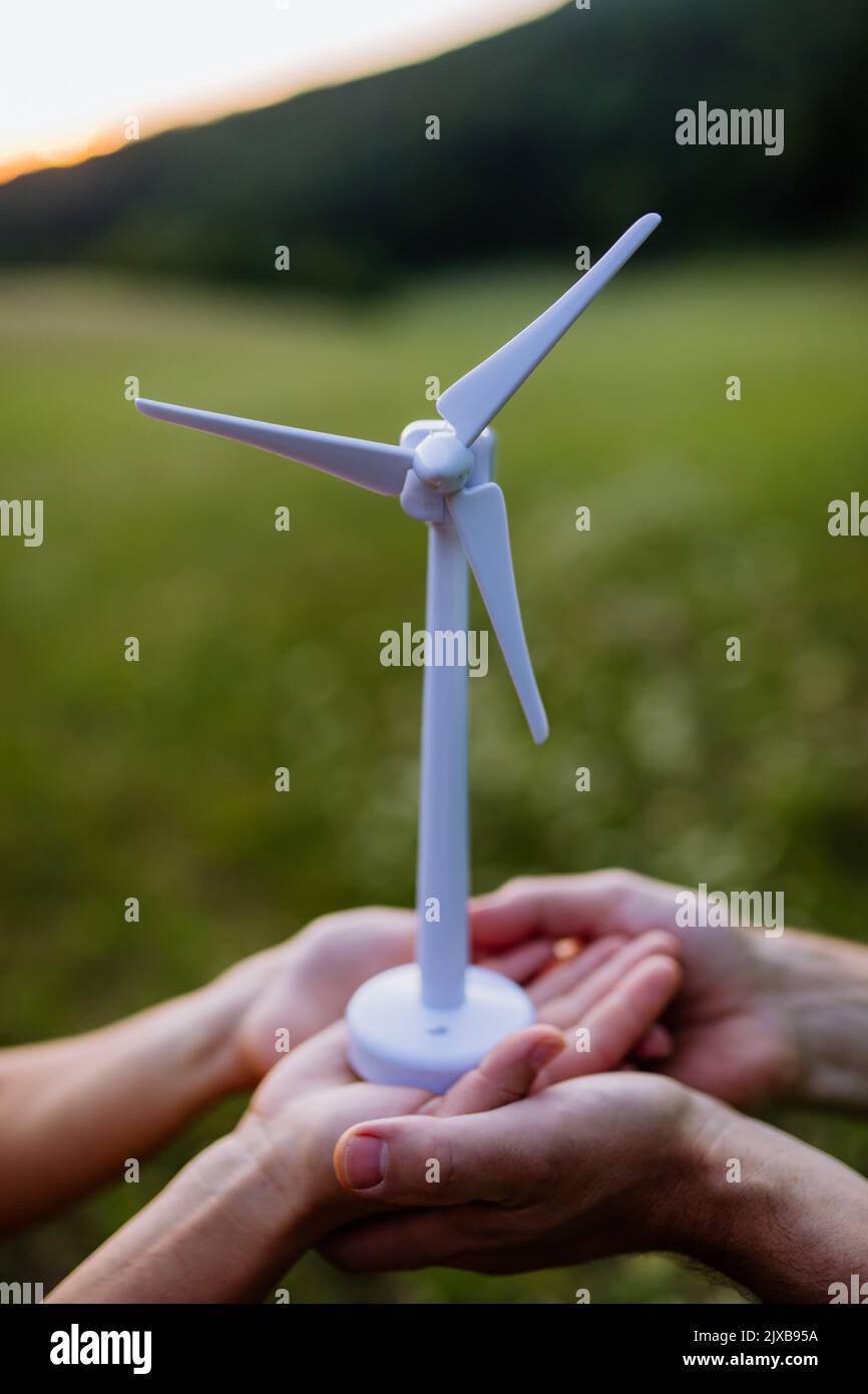 Gros plan de couple debout dans la nature avec le modèle de l'éolienne. Concept d'écologie Ressources futures et renouvelables. Banque D'Images