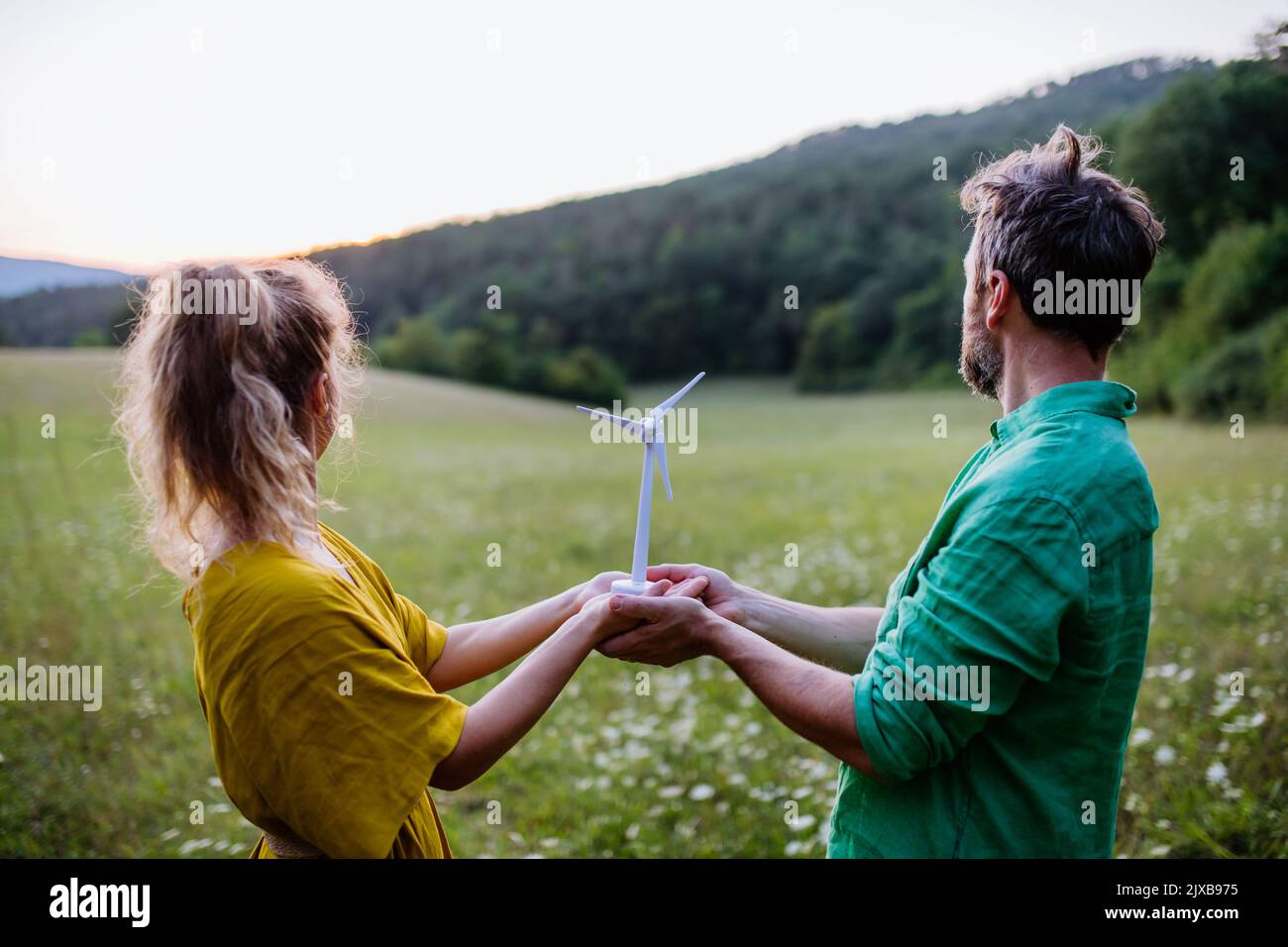 Couple debout dans la nature avec modèle d'éolienne. Concept d'écologie Ressources futures et renouvelables. Banque D'Images