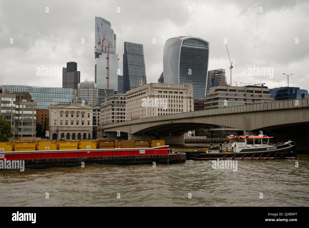 La ville de Londres avec des barges chargées de conteneurs sur la Tamise. La traction du remorqueur est appelée récupération. Banque D'Images