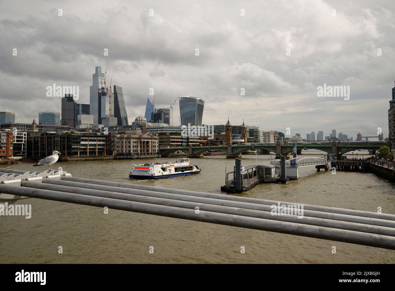 La ville de Londres depuis le Millennium Bridge avec un bateau touristique qui descend le long de la rivière. Banque D'Images