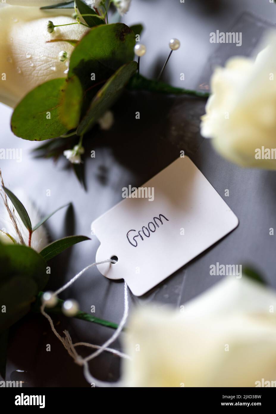 L'étiquette du marié sur la fleur en relief de mariage favorise la fleur à attacher au groomsman à la célébration. Fleurs roses à bord en attente d'être portées. Banque D'Images