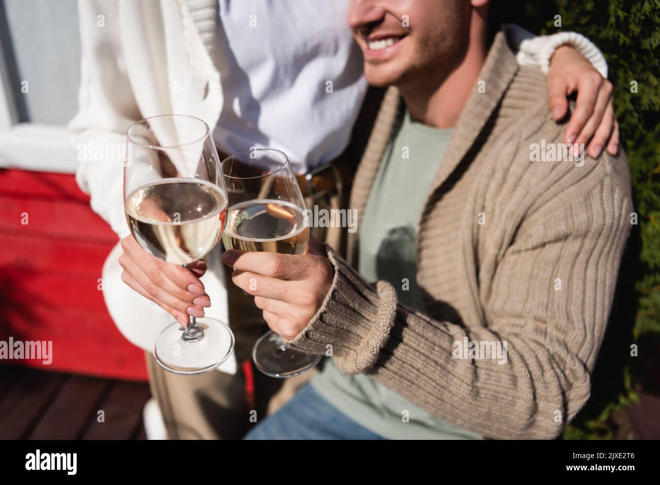 Vue rognée d'un couple dans des cardigans chauds avec dégustation de vin à l'extérieur, image de stock Banque D'Images