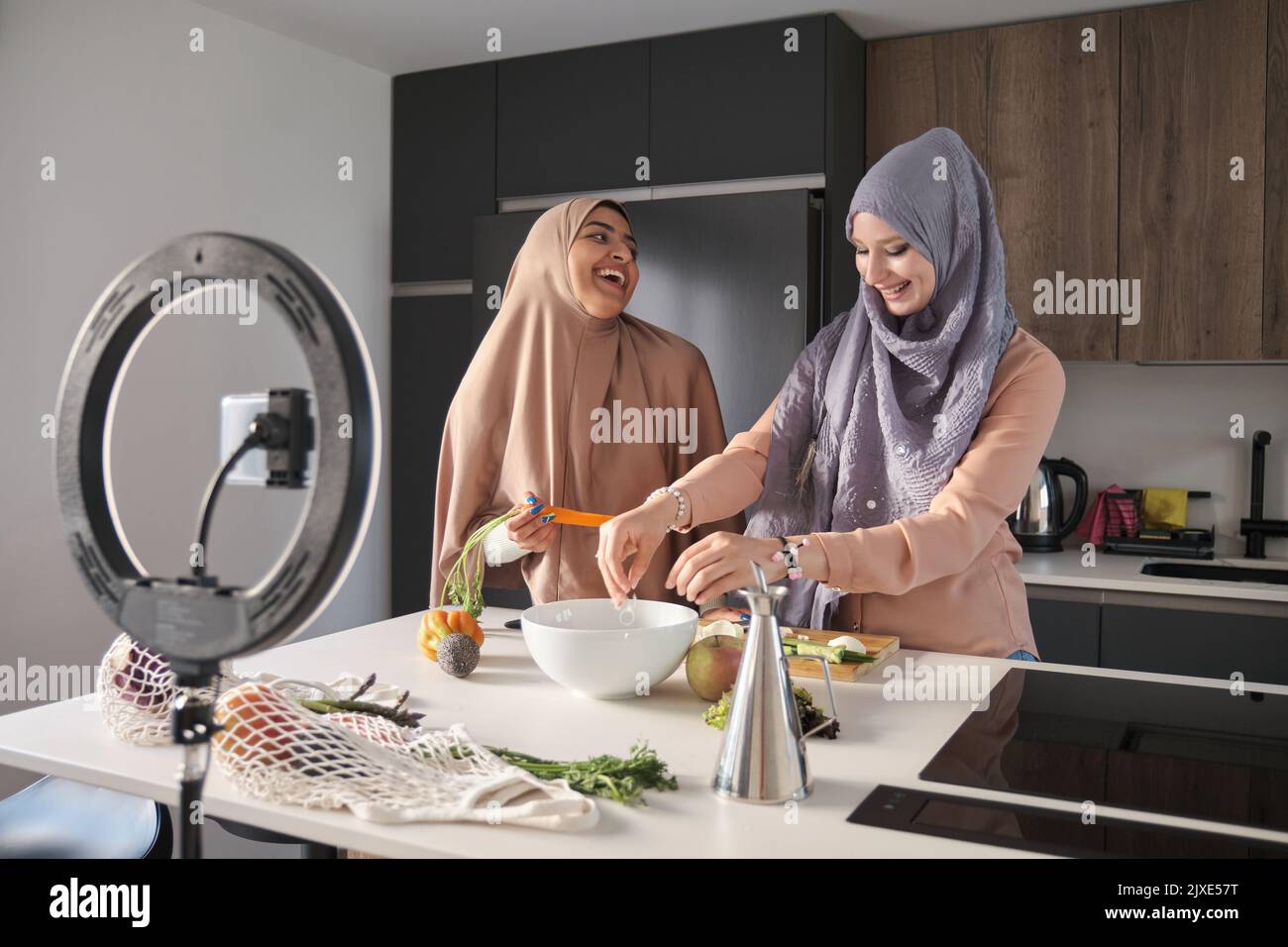 Deux bûcherons musulmans rient tout en préparant une salade dans la cuisine. Banque D'Images
