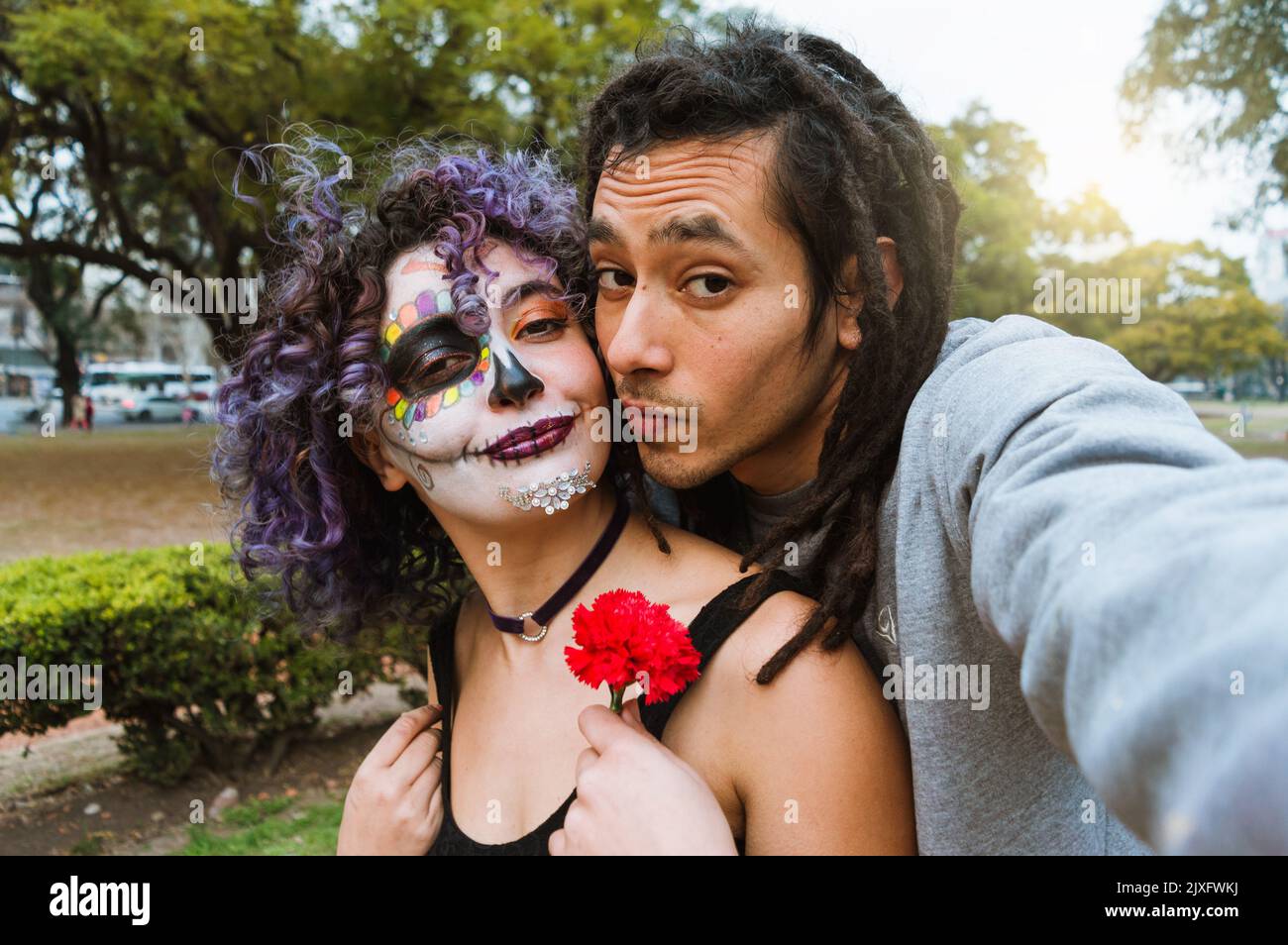 couple hétérosexuel regardant l'appareil-photo appréciant de prendre un selfie dans le parc le jour des morts, téléphone perspective. Banque D'Images