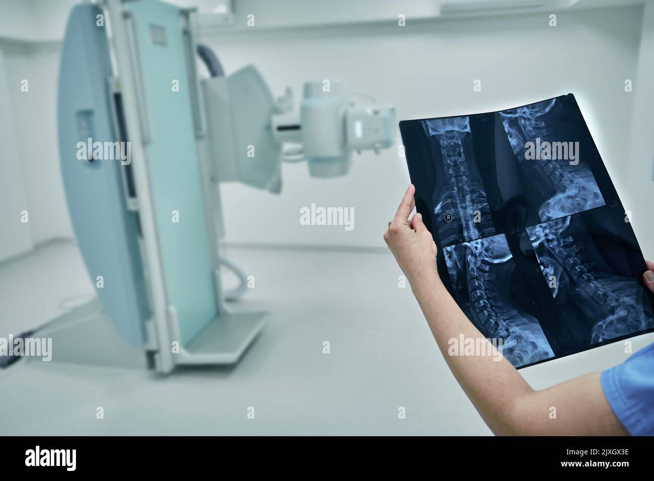 Radiologue examinant et analysant les rayons X du rachis cervical du patient sur fond de salle de radiologie moderne à l'hôpital Banque D'Images