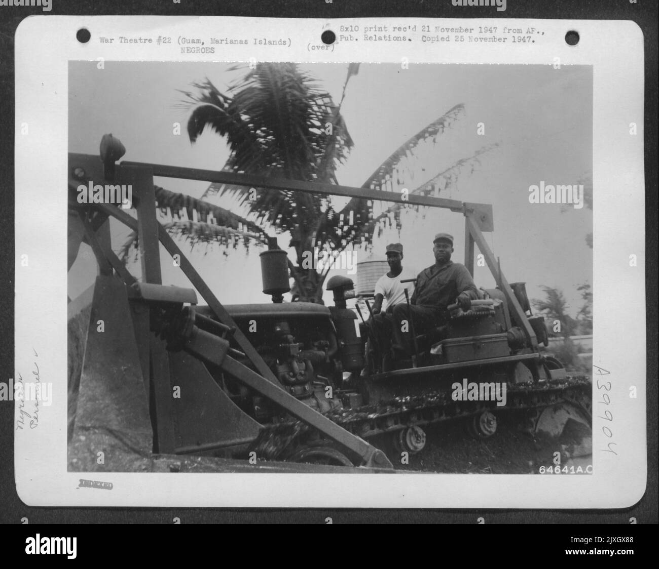 Sgt. C. B. Williams, 518, rue Roosevelt, Longview (Texas) et Cpl. William Goodwin, Abbeville, en Caroline du Sud, est présenté aux engins d'Un bulldozer tout en défaisant Jungle dans le quartier général de la vingtième Force aérienne, à Guam, dans les îles Marianas. Seulement Thro Banque D'Images