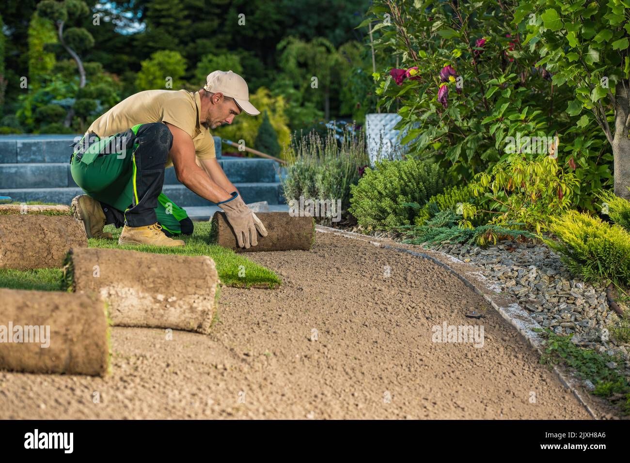 Travailleur de jardin et paysagiste professionnel caucasien installation de tourfs d'herbe naturelle fraîche à partir de rouleaux. Banque D'Images