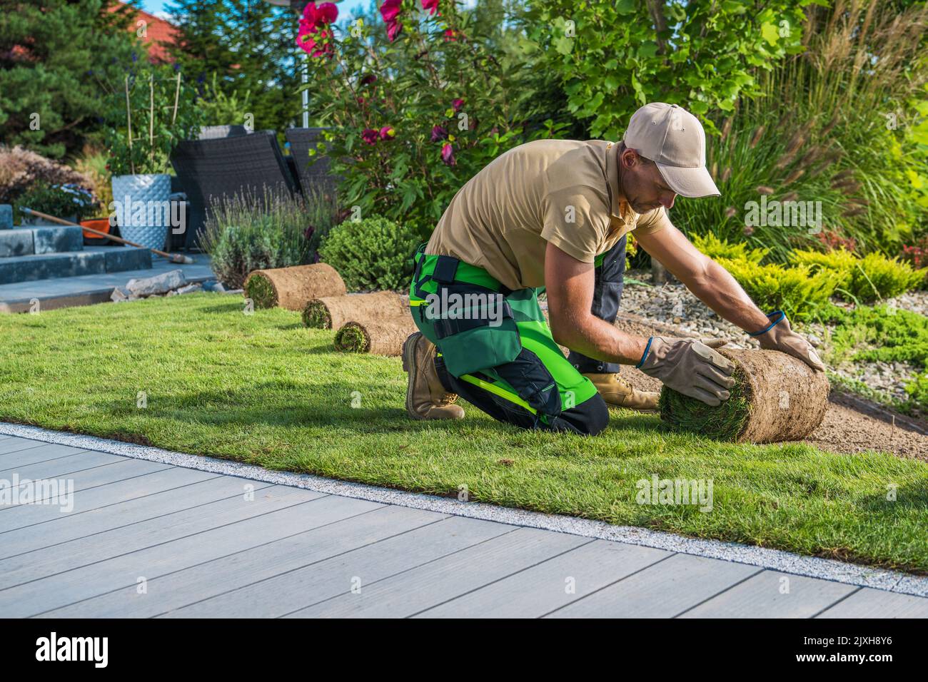 Thème résidentiel paysagiste. Paysagiste caucasien professionnel installant de nouvelles tourfs d'herbe dans le jardin d'arrière-cour. Banque D'Images