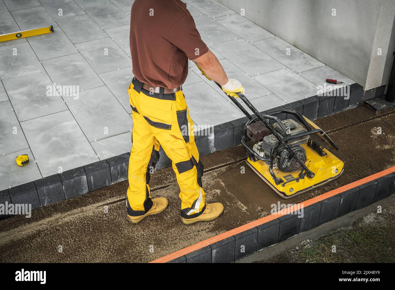 Chantier de construction patio en béton. Activer l'autosurveillance du compacteur de sol à plaque vibrante. Thème industriel. Banque D'Images