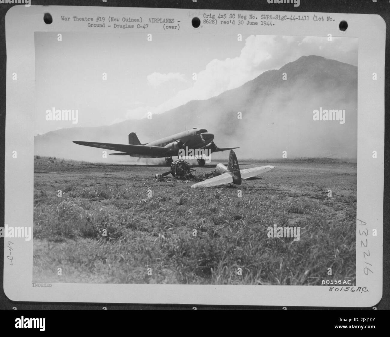 Le premier Douglas américain C-47 débarque sur Cyclops Airifeld, Hollandia, Nouvelle-Guinée, taxis en haut de la bande après Un zéro japonais brûlé. 28 avril 1944. Banque D'Images