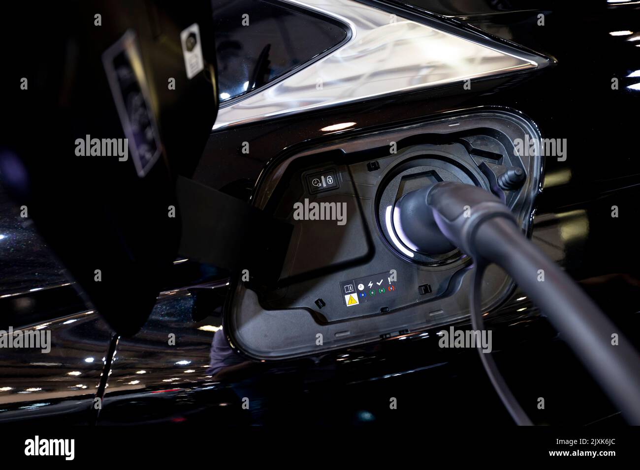 Voiture électrique branchée à une station de charge de véhicule électrique. Véhicule électrique à une station de charge avec le câble d'alimentation branché et en charge. Banque D'Images