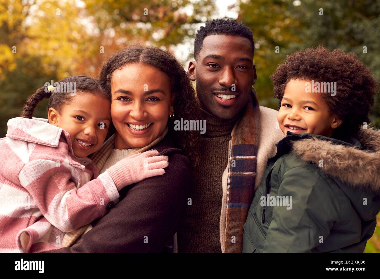 Portrait de famille souriante en train de s'amuser à traverser la campagne contre les arbres d'automne ensemble Banque D'Images