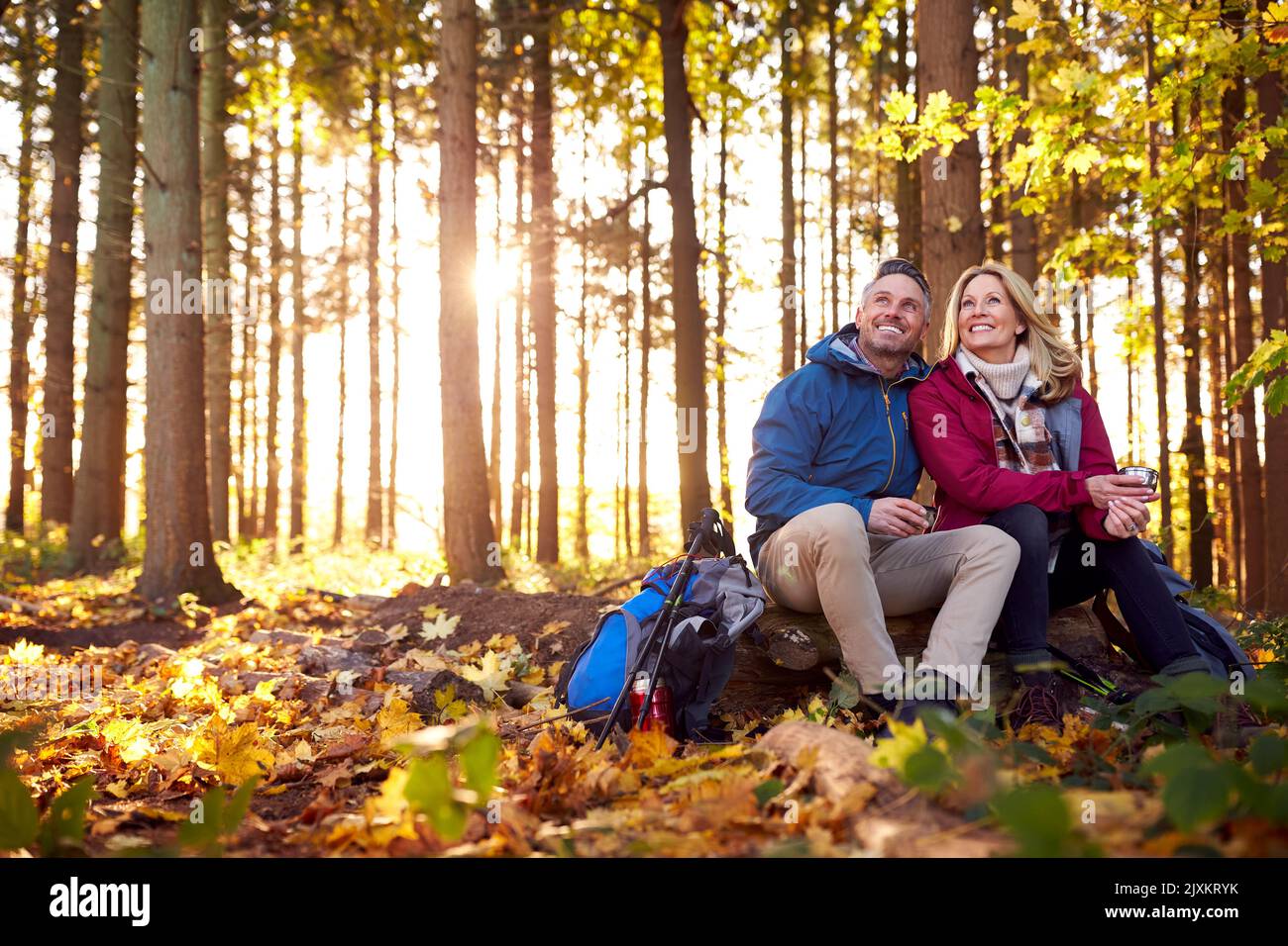 Couple retraité mature Arrêtez-vous pour vous reposer et boire un verre chaud lors d'une promenade dans la campagne d'automne ou d'hiver Banque D'Images