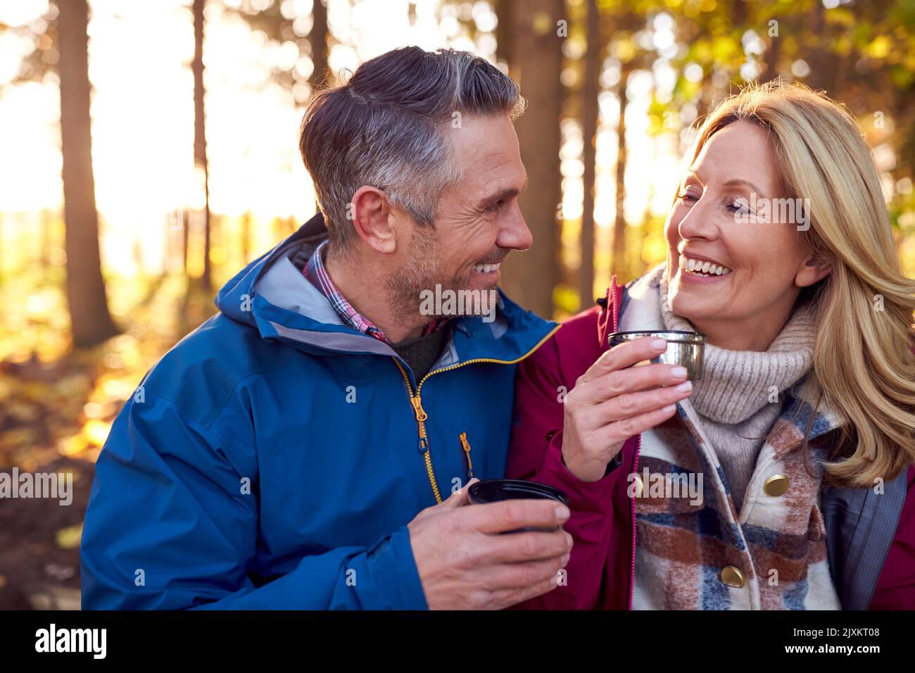 Couple retraité mature Arrêtez-vous pour vous reposer et boire un verre chaud lors d'une promenade dans la campagne d'automne ou d'hiver Banque D'Images