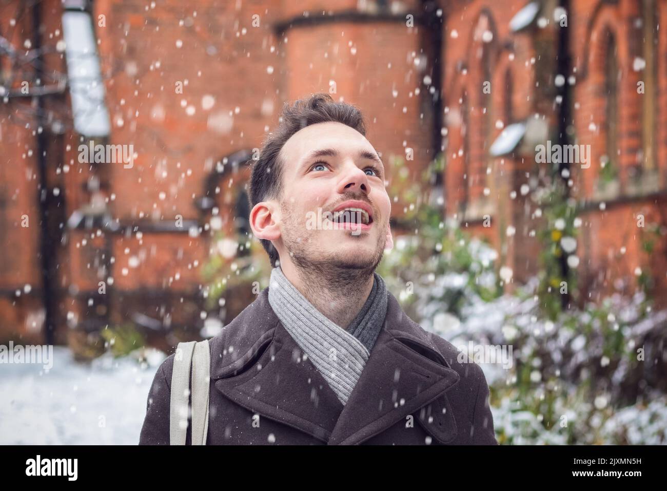 Portrait d'un homme souriant heureux émerveillé par la neige qui tombe en hiver Banque D'Images