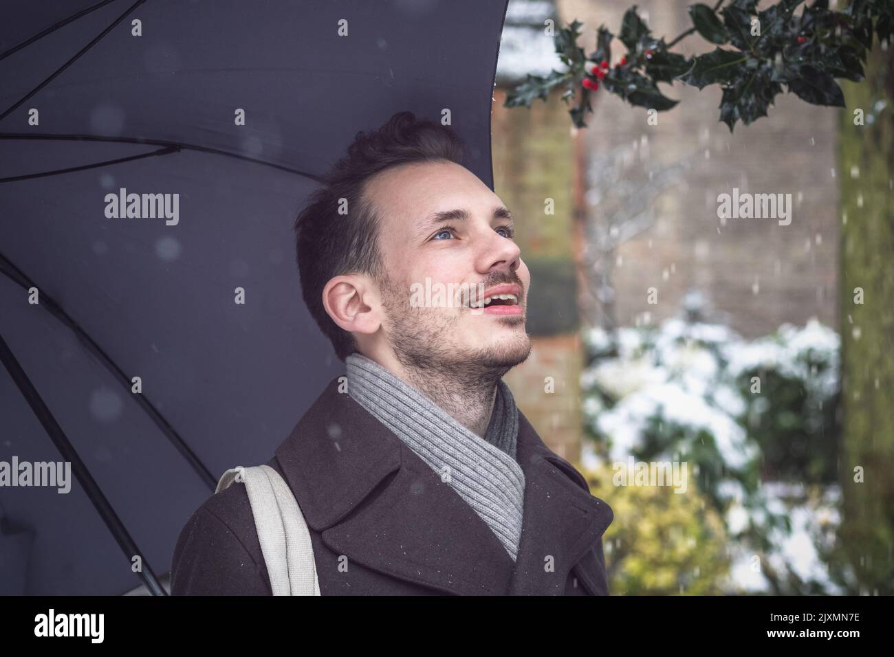 Portrait d'un beau jeune homme avec parapluie en hiver neige Banque D'Images