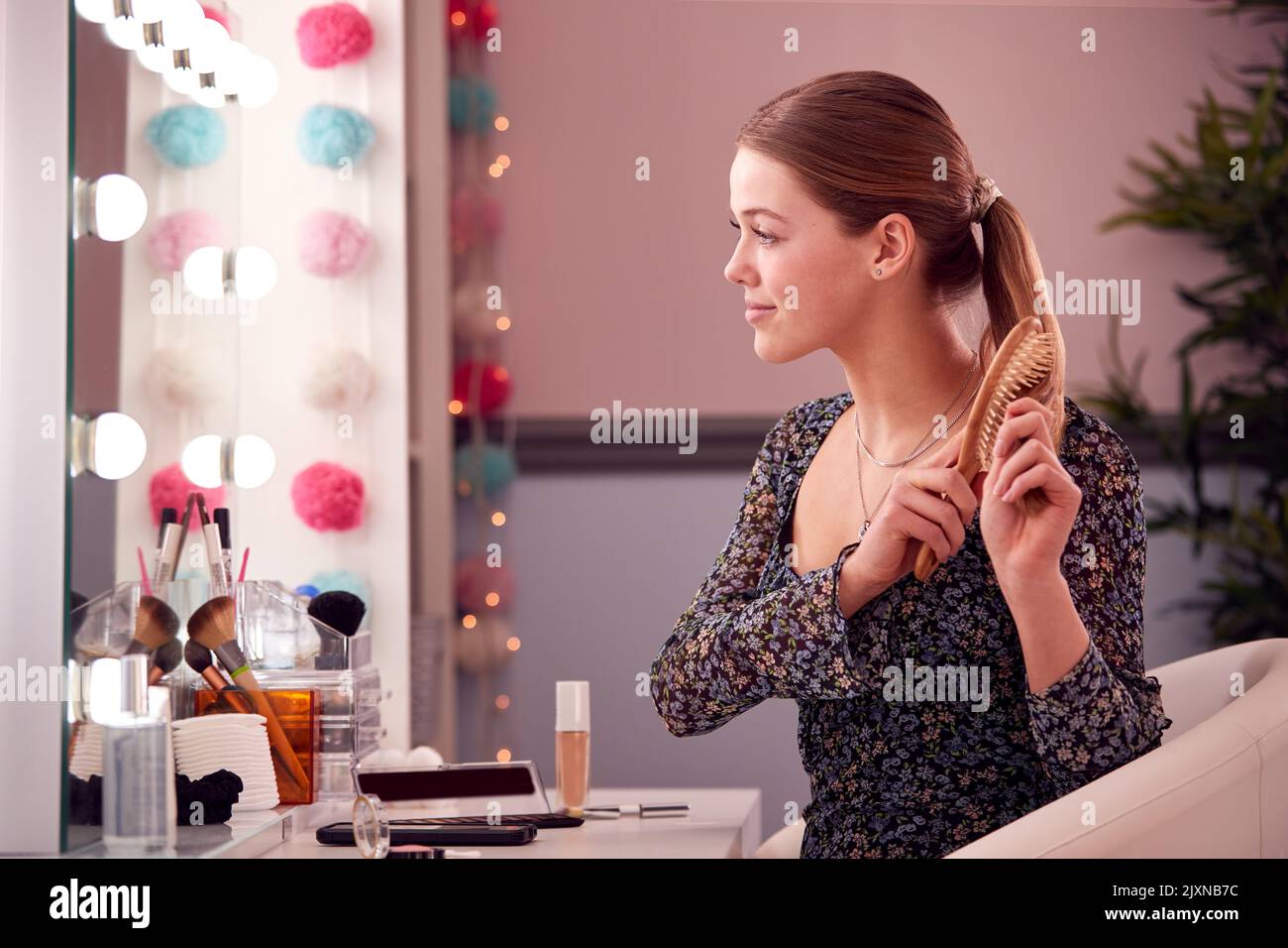 Teenage Girl se brossant les cheveux dans le miroir de maquillage dans la chambre à la maison Banque D'Images